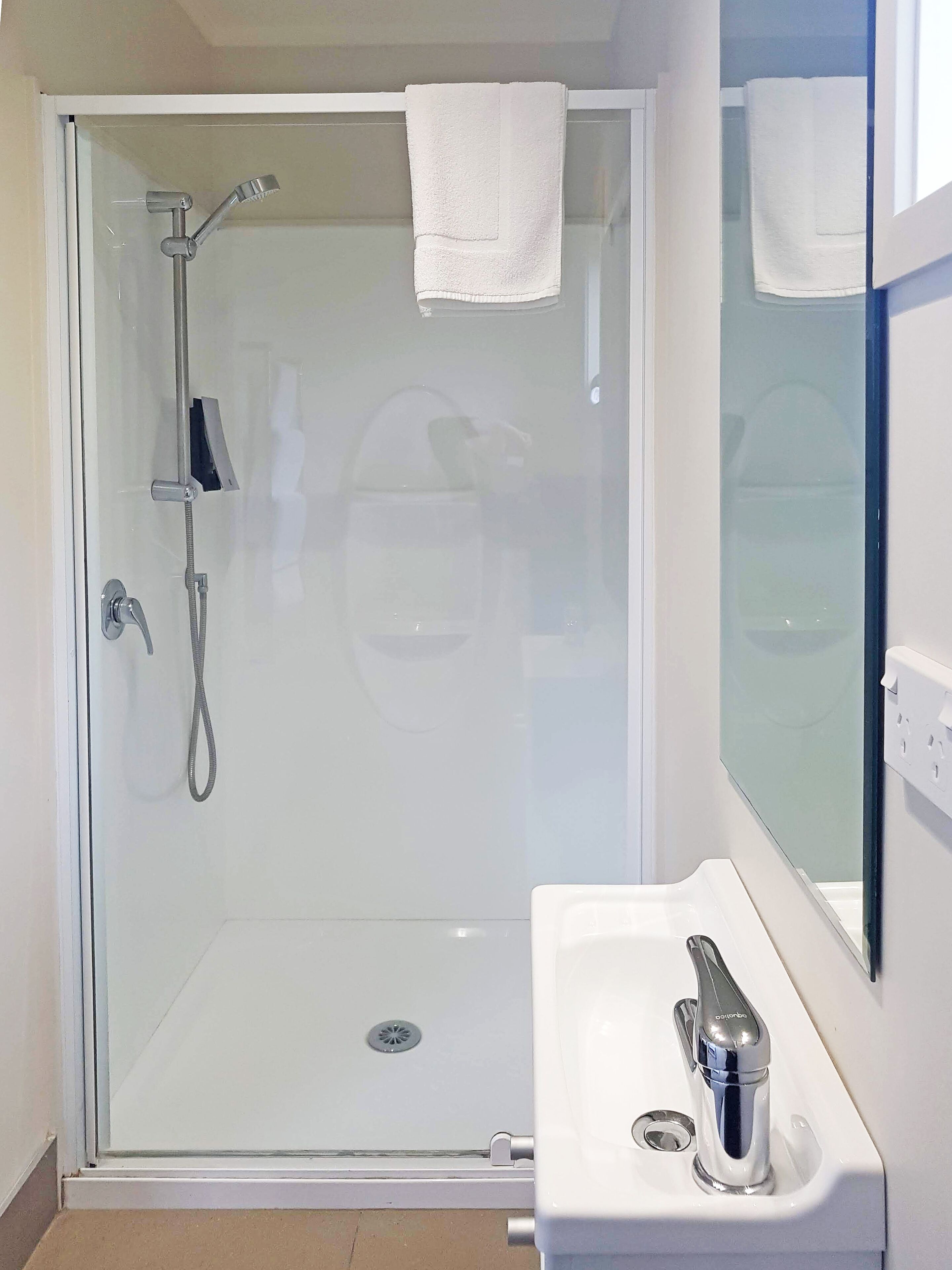 A modern bathroom with a glass-enclosed shower, a white sink, and a mirror.