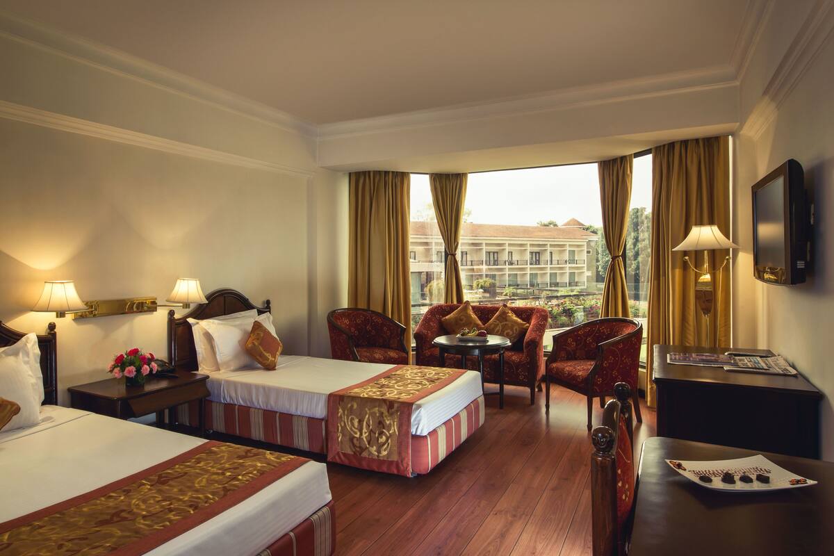 A hotel room with two beds, a sofa, a small table, and a TV.