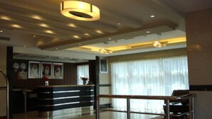 A hotel lobby with a reception desk, a glass railing, and a large window with curtains. - Paragon Hotel Apartments (Abu Dhabi)