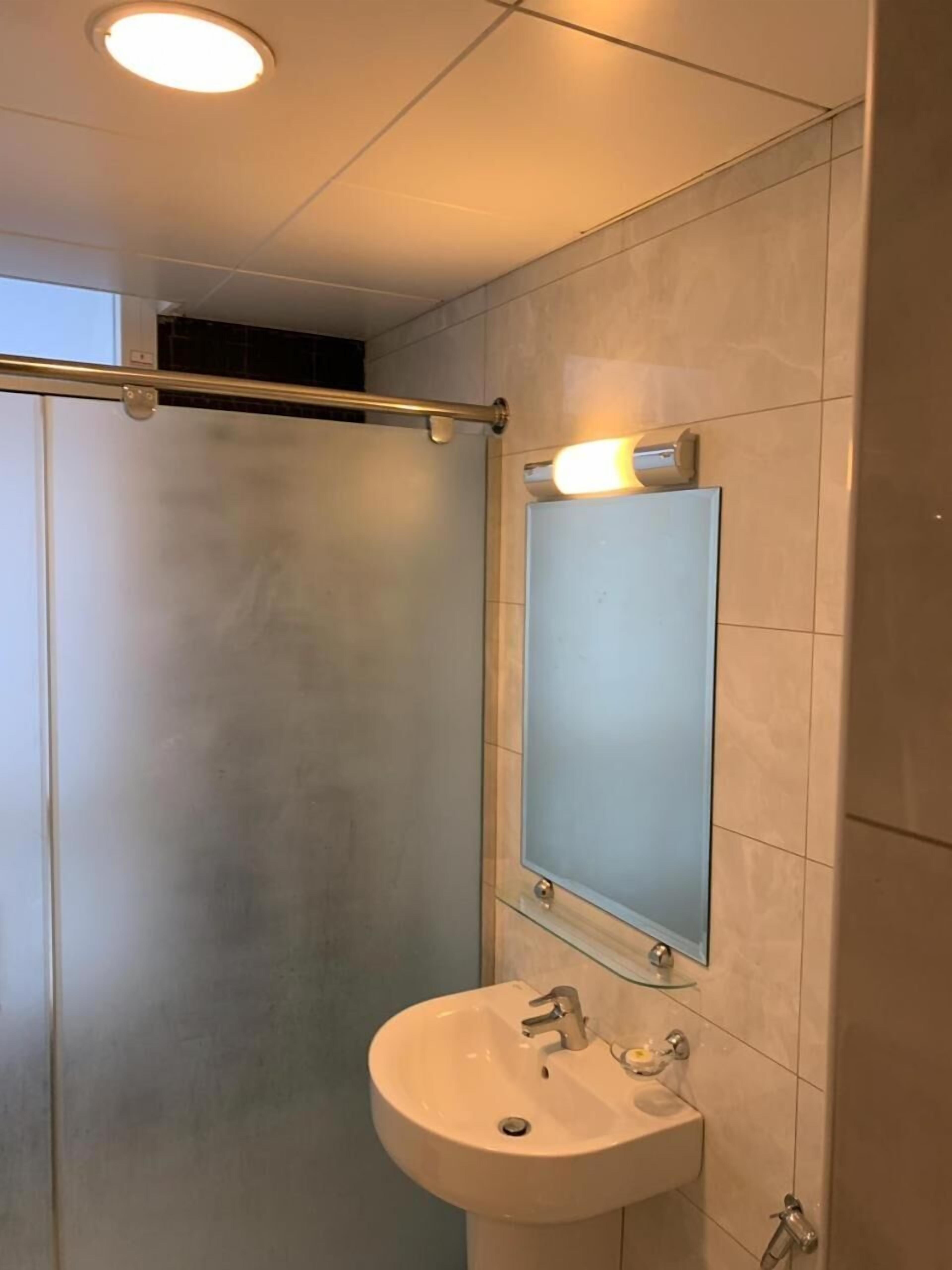 Un baño moderno con cabina de ducha de vidrio, un lavabo blanco y un espejo encima.