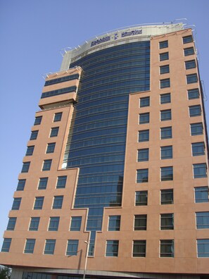 A tall hotel building with a curved glass facade and a sign reading "Paragon Hotel".