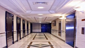 A long, well-lit hallway with marble flooring, doors, and elevators. - Paragon Hotel Apartments (Abu Dhabi)