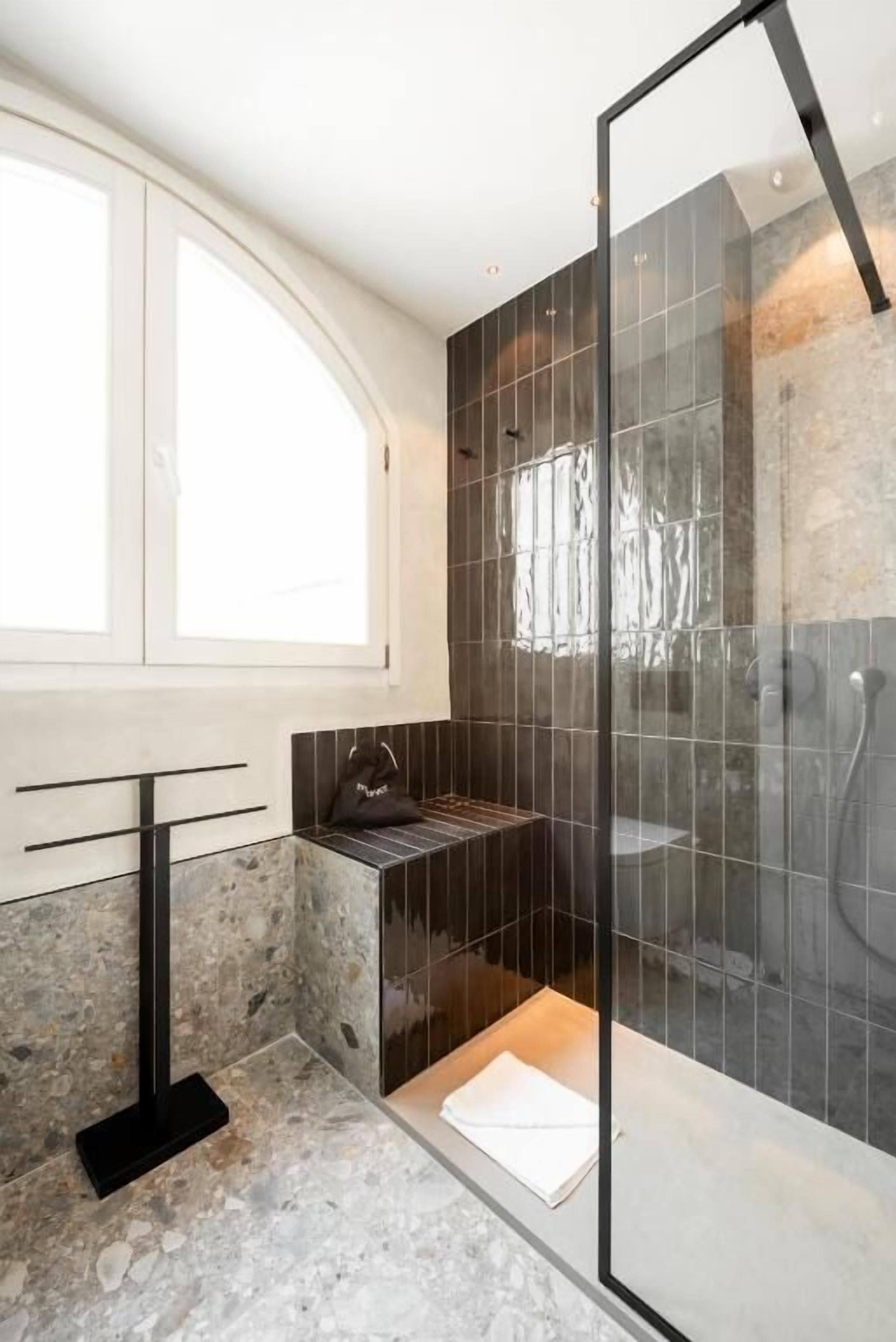 Un bagno moderno con doccia vetrata, lavabo in marmo e finestra che offre luce naturale.