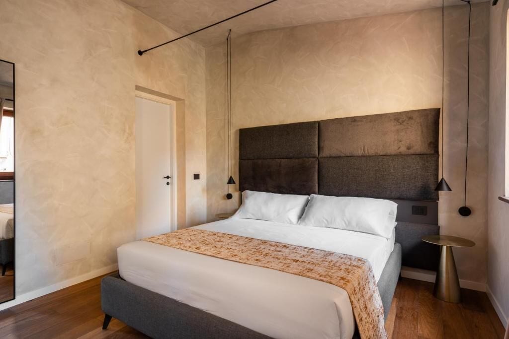 A modern bedroom with a large bed, a dark headboard, and a small bedside table.