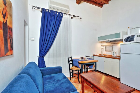 Um espaço compacto com sofá, mesa de jantar e cozinha compacta.