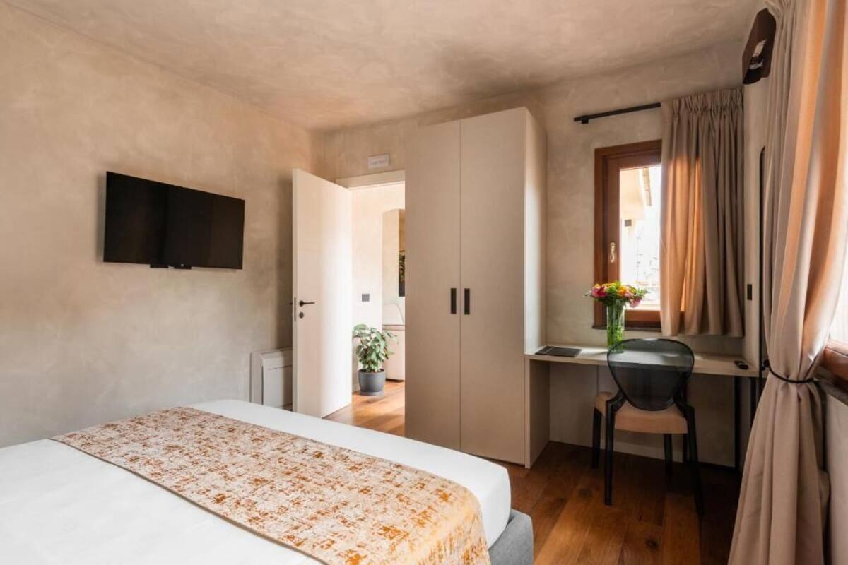 A compact bedroom with a bed, a desk, and a TV mounted on the wall.