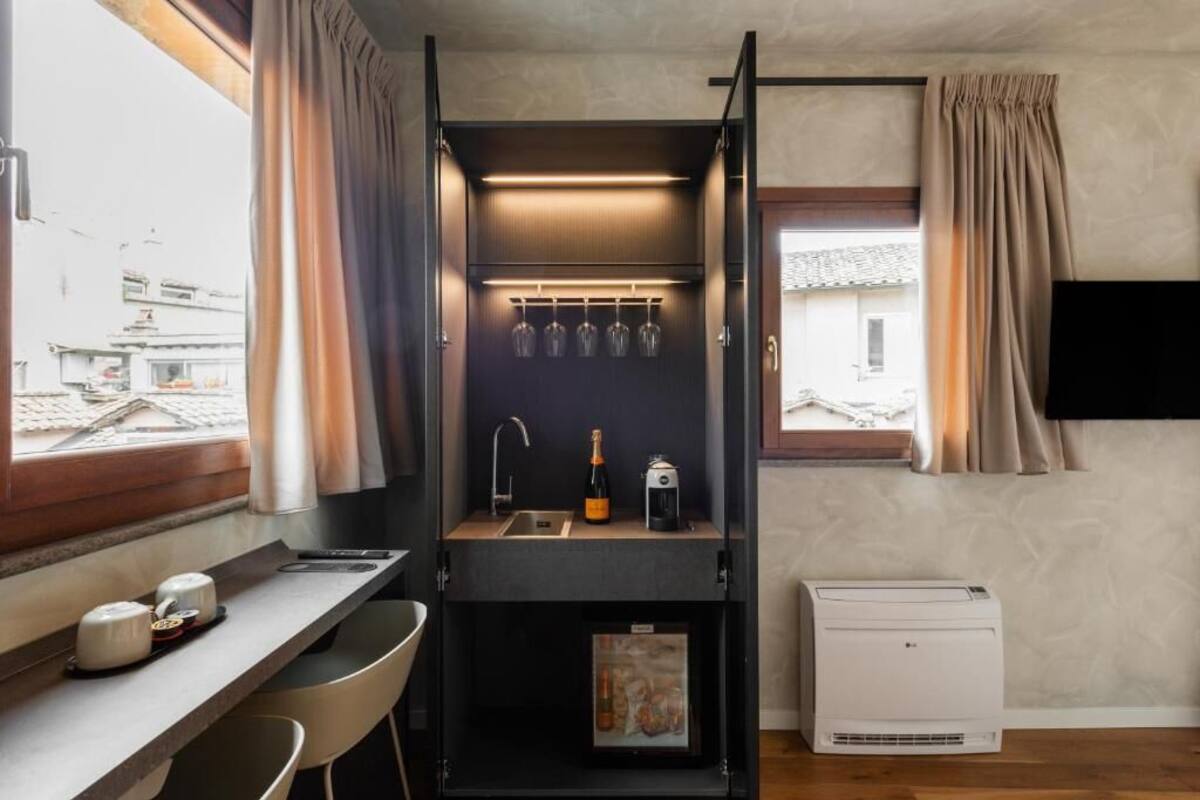 A compact kitchenette with a built-in sink, a wine bottle, and a small fridge.