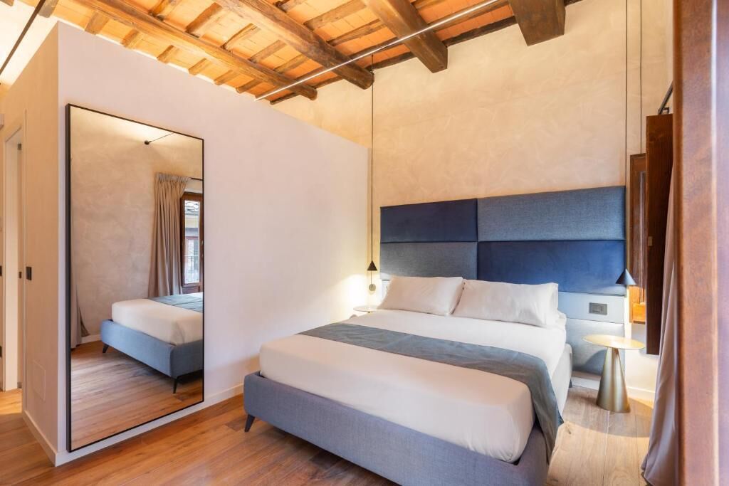 A modern bedroom with a large bed, a mirror, and a wooden ceiling.