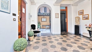 Un corridoio con pavimento a motivi esagonali, una porta in legno, una panca e un quadro appeso al muro.