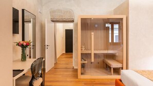 Una camera moderna con una scrivania in legno, una sedia, un letto e un angolo doccia con pareti in vetro.