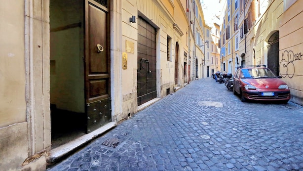 Una strada acciottolata con un'auto rossa parcheggiata a destra.
