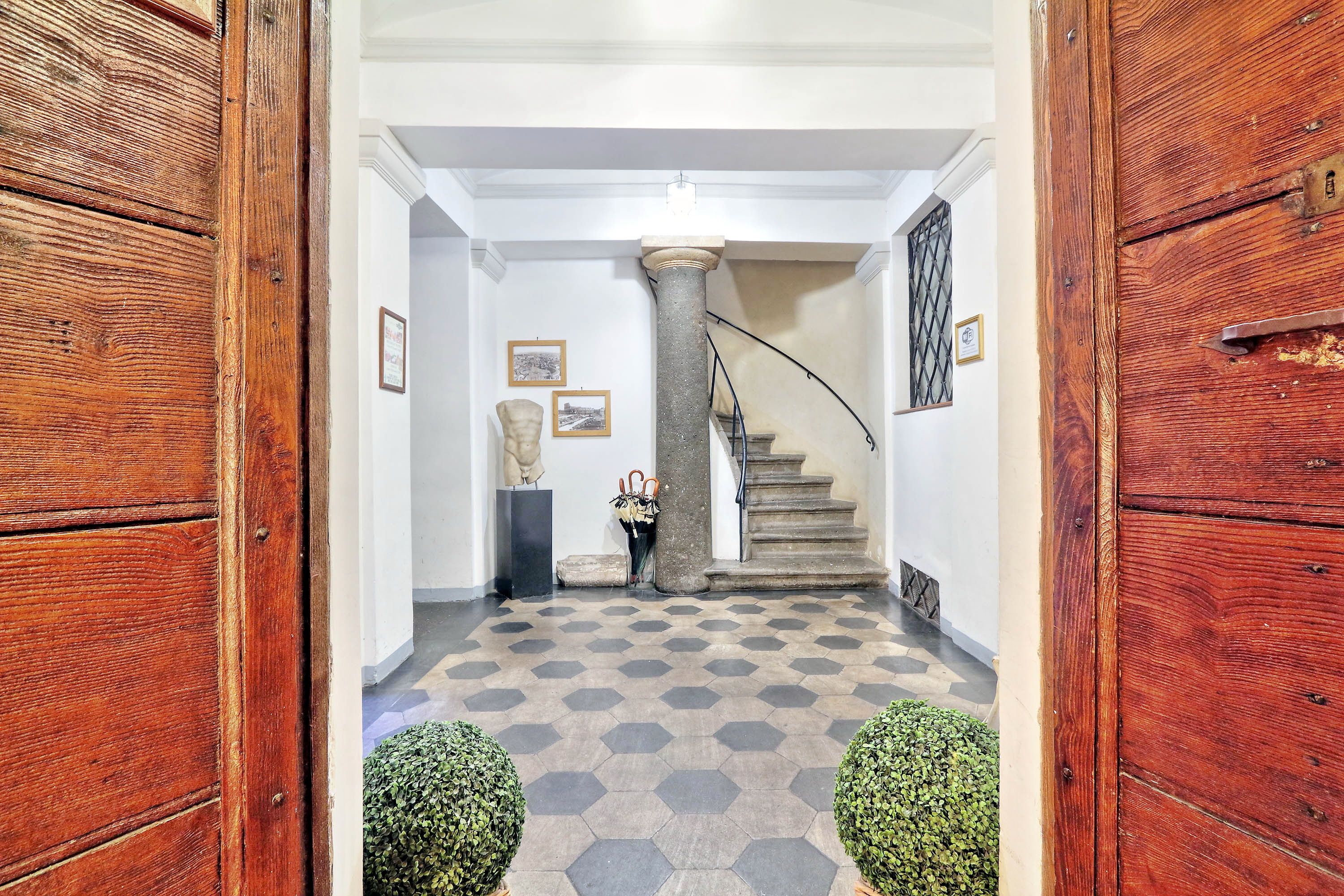 A hallway with a wooden door, a staircase, and hexagonal patterned flooring.