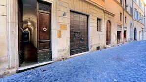 Una stretta strada acciottolata con un edificio caratterizzato da un'ampia porta in legno e un cancello in metallo.