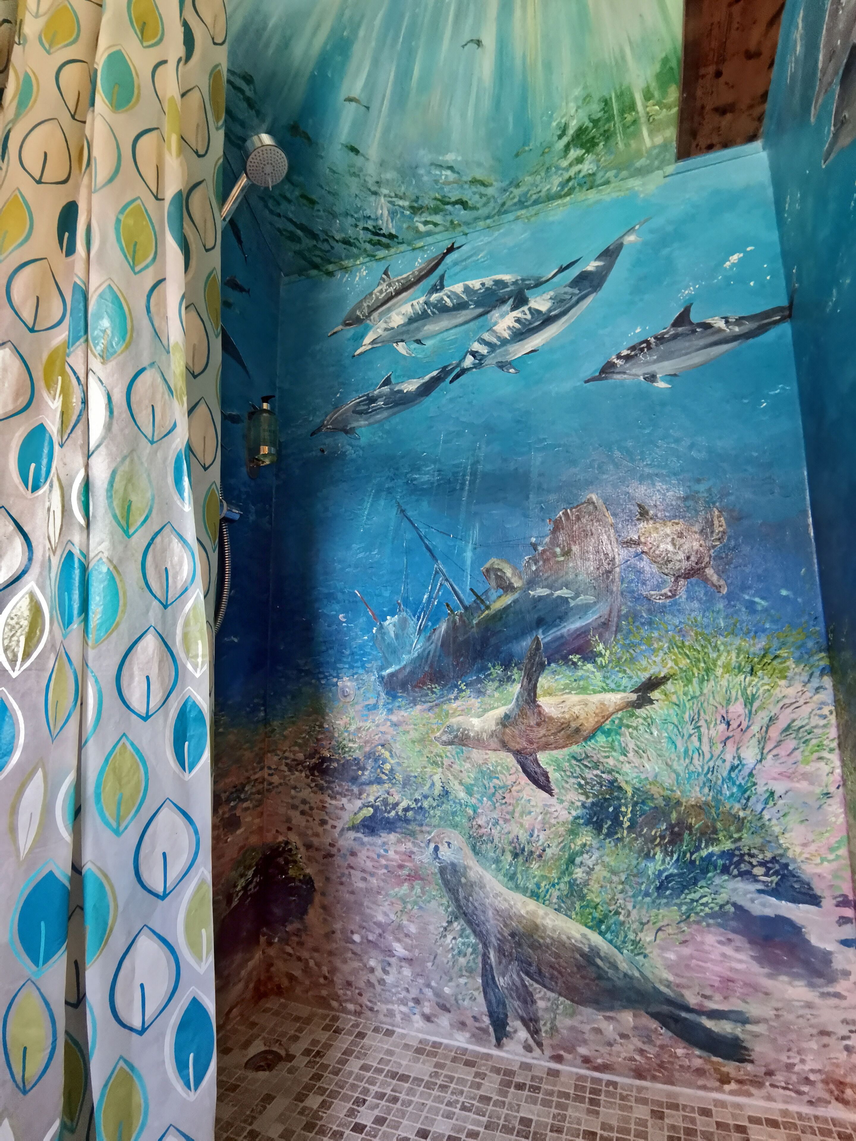 Un mural subacuático en un baño, con vida marina y un naufragio.