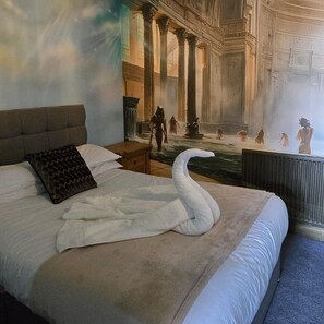 A bedroom with a large bed, a swan-shaped pillow, and a mural of classical architecture. - Stonehenge Inn (Salisbury)