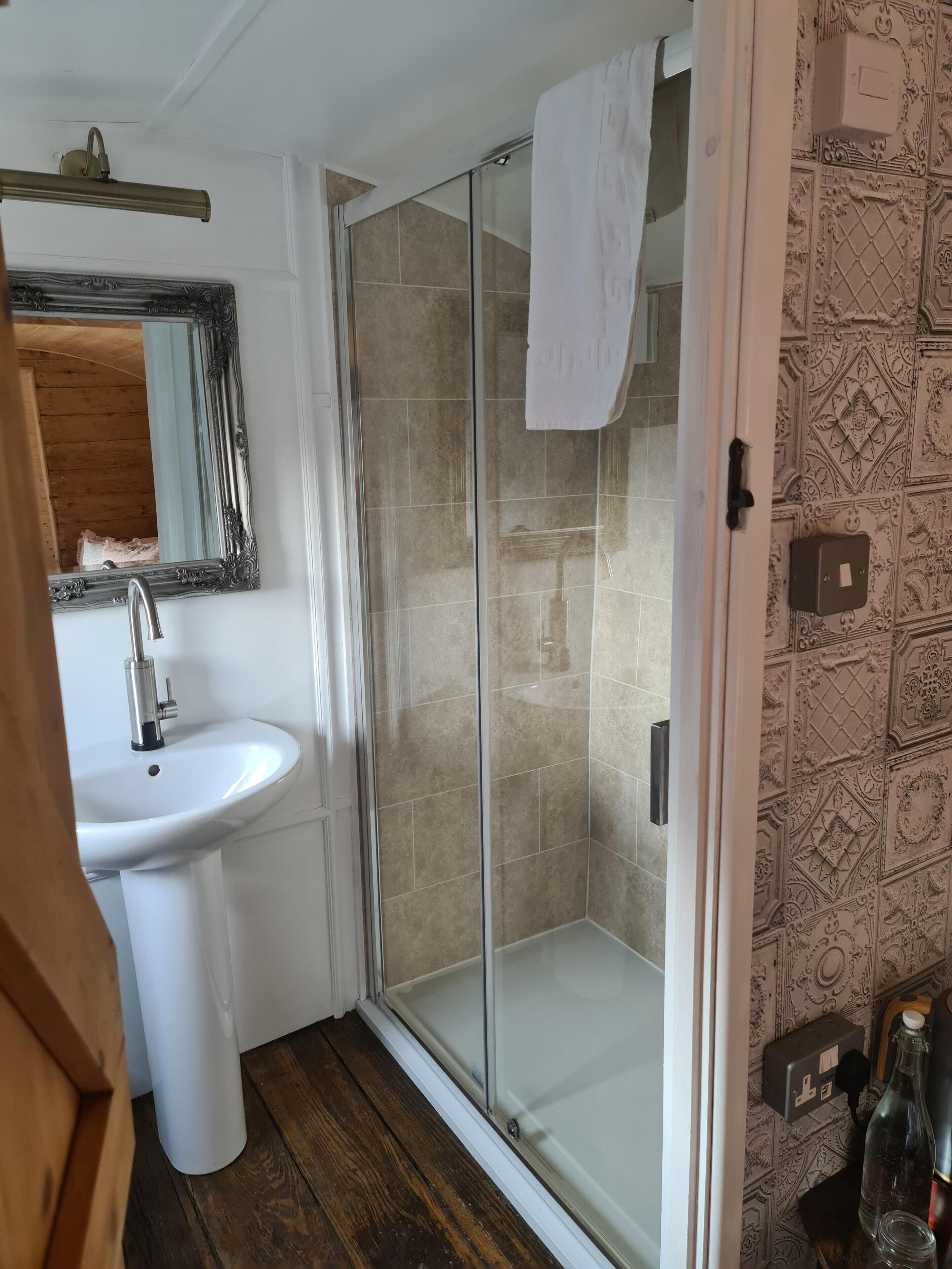 A bathroom with a white sink, a glass shower enclosure, and patterned wall tiles.