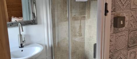 A bathroom with a white sink, a glass shower enclosure, and patterned wall tiles.