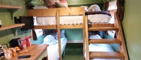 A bunk bed room with a wooden desk and shelves, a ceiling mural, and a staircase.