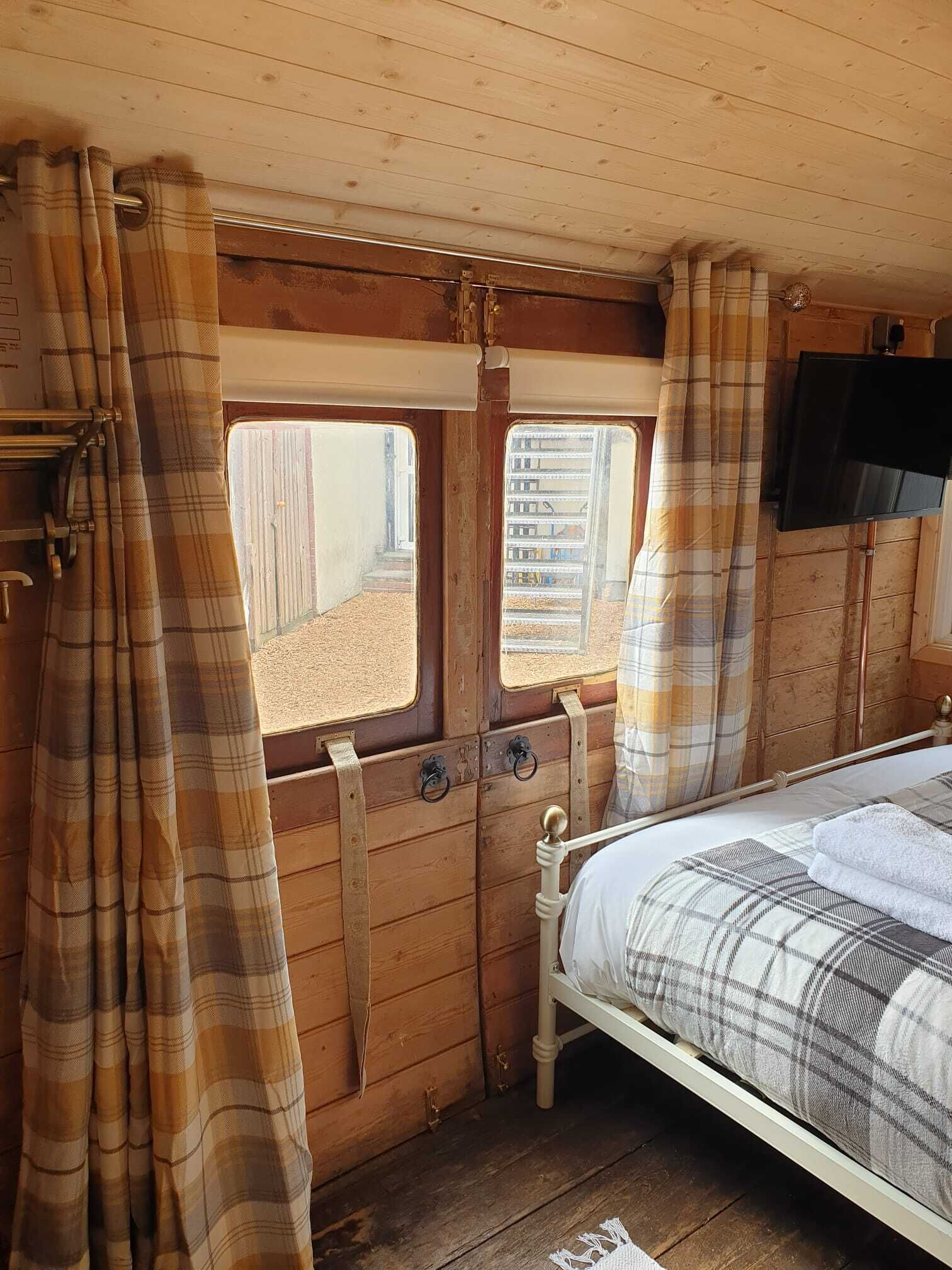 A cozy bedroom with a bed, wooden walls, and a window with curtains.