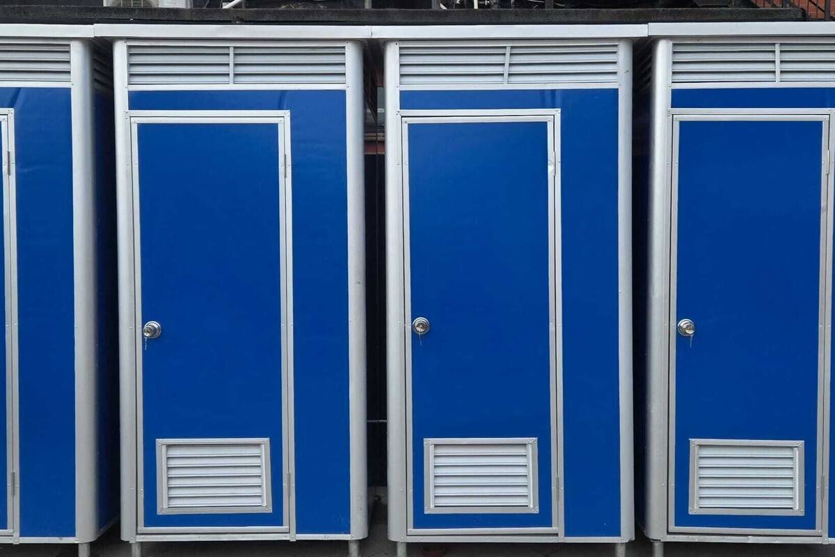 Four blue portable toilets with white frames and ventilation grilles.