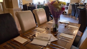 A dining table set with cutlery and napkins, surrounded by chairs in a restaurant setting. - Stonehenge Inn (Salisbury)