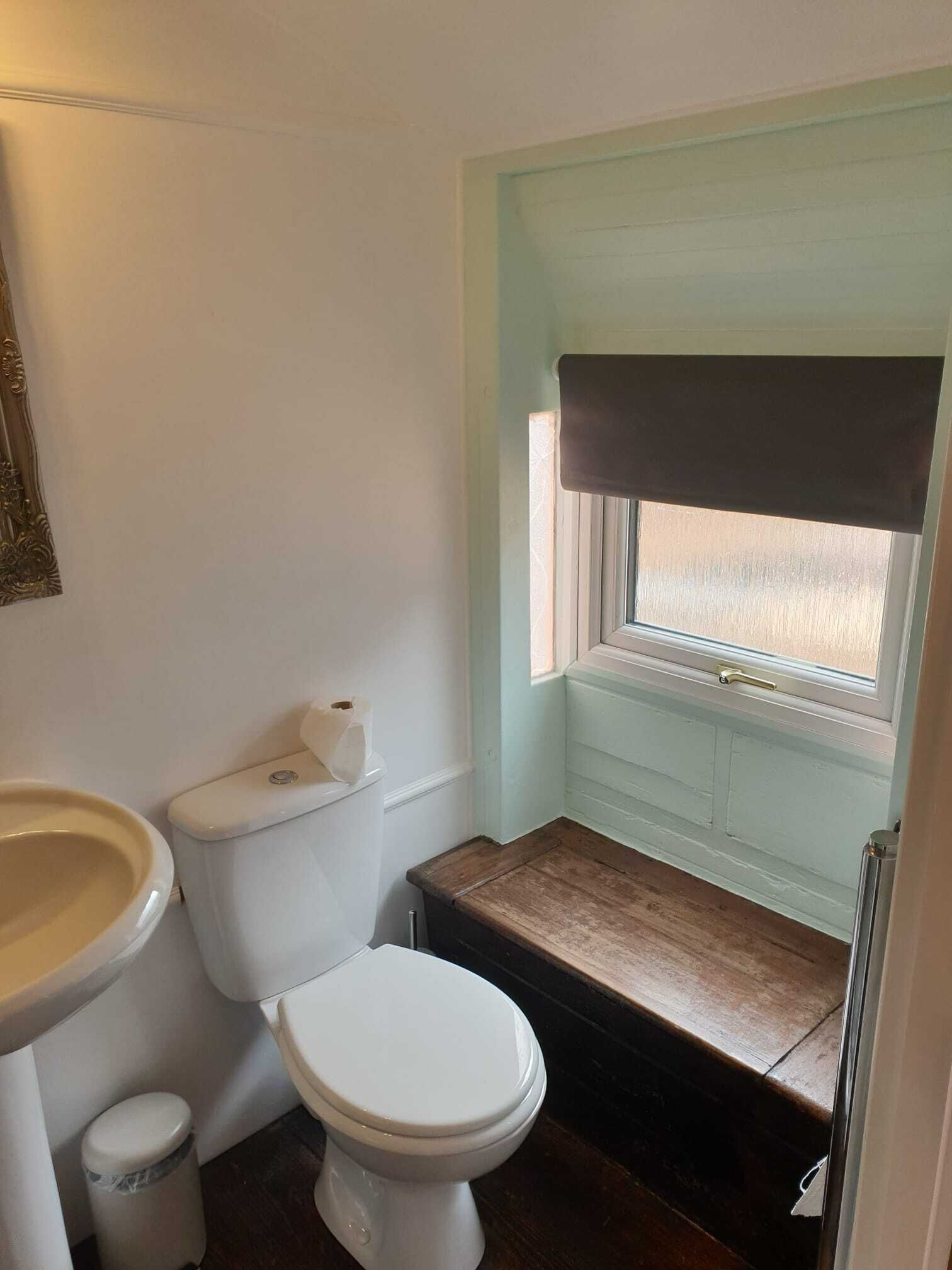 Un baño pequeño con inodoro, lavamanos y ventana.