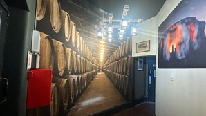 A corridor lined with wooden barrels, a red fire extinguisher, and a painting on the wall. - Stonehenge Inn (Salisbury)