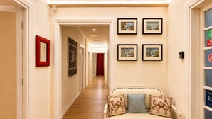 A hallway with a sofa, framed pictures, and a door. - Roma in una Stanza GuestHouse (Rome)