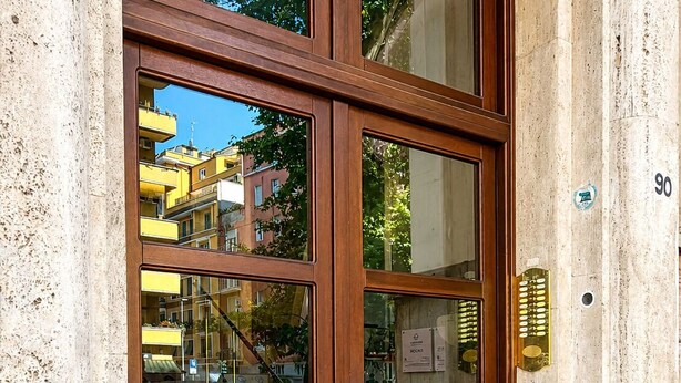 A building entrance with a wooden door, glass panels, and a brass handle. - Roma in una Stanza GuestHouse (Rome)