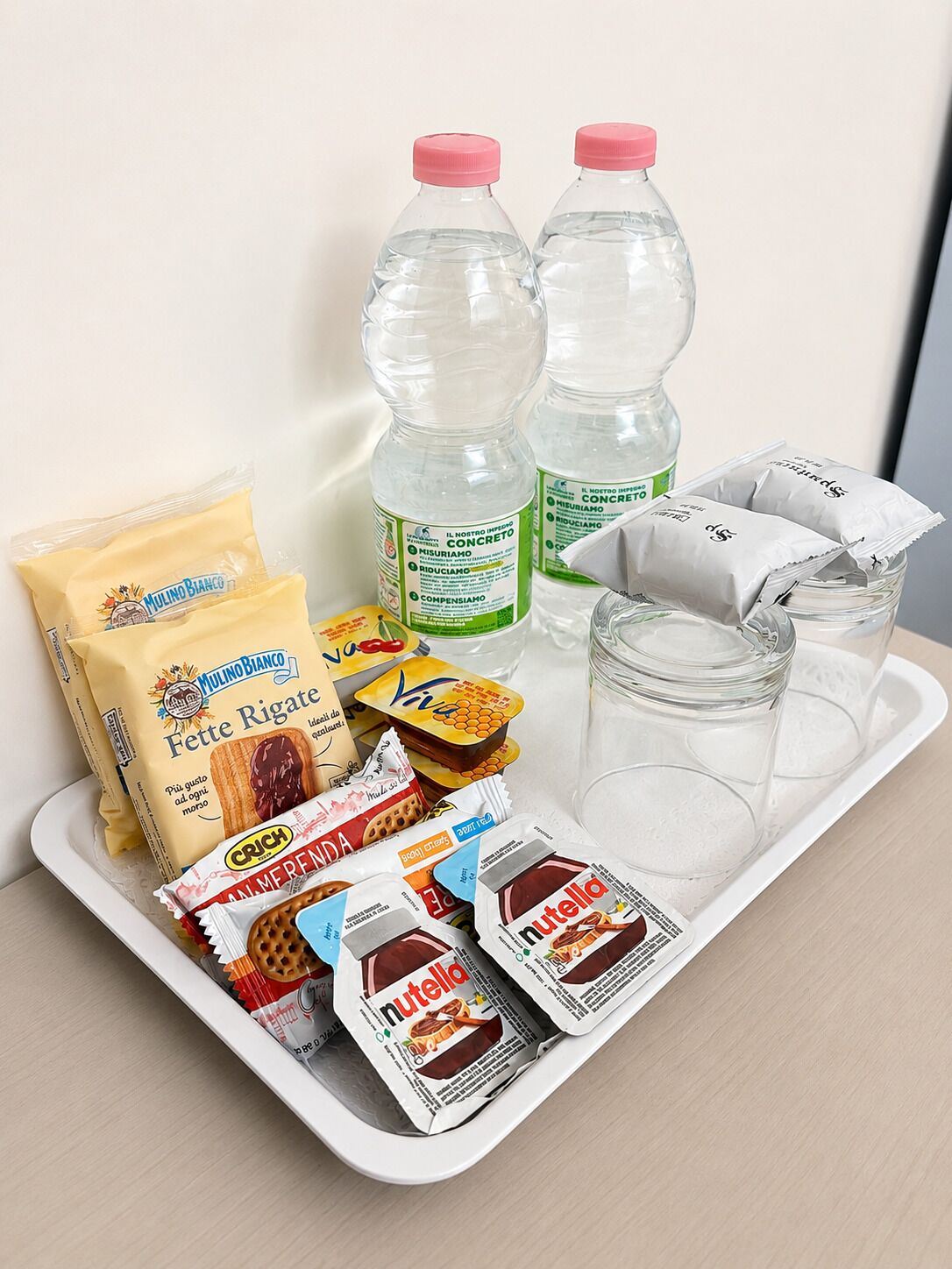Un plateau contenant des aliments, deux bouteilles d’eau et un bocal en verre.