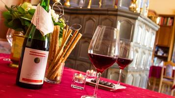 Une table avec une bouteille de vin, des verres, des gressins et des bougies.