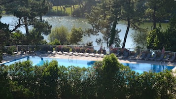 Una piscina techada, una piscina al aire libre, sombrillas