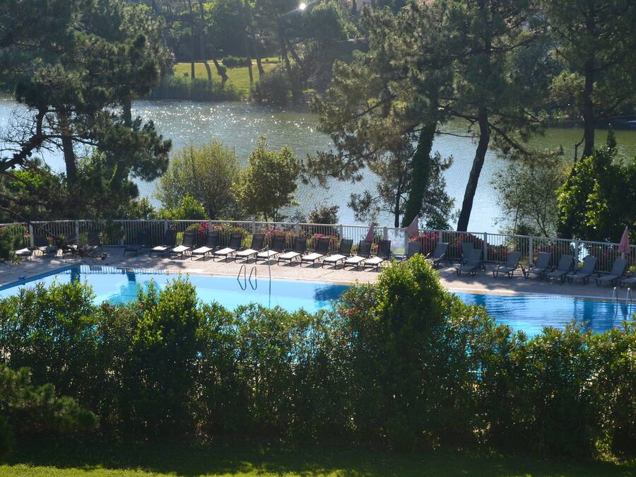 Zona de piscina con sillones de descanso y vista a un lago.