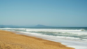 A beach with a clear sky, waves, and distant mountains. - Hôtel Maison Chiberta (Anglet)
