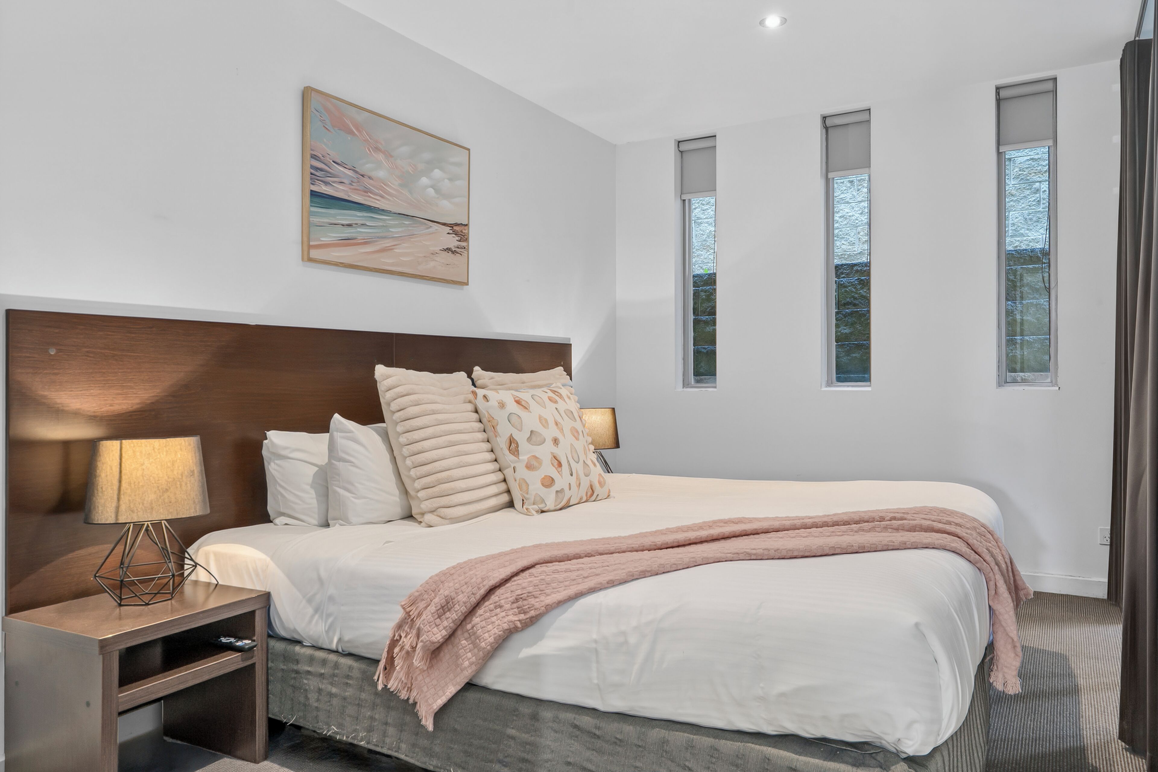Una camera da letto moderna con un letto grande, un comodino, una lampada e un quadro appeso al muro.