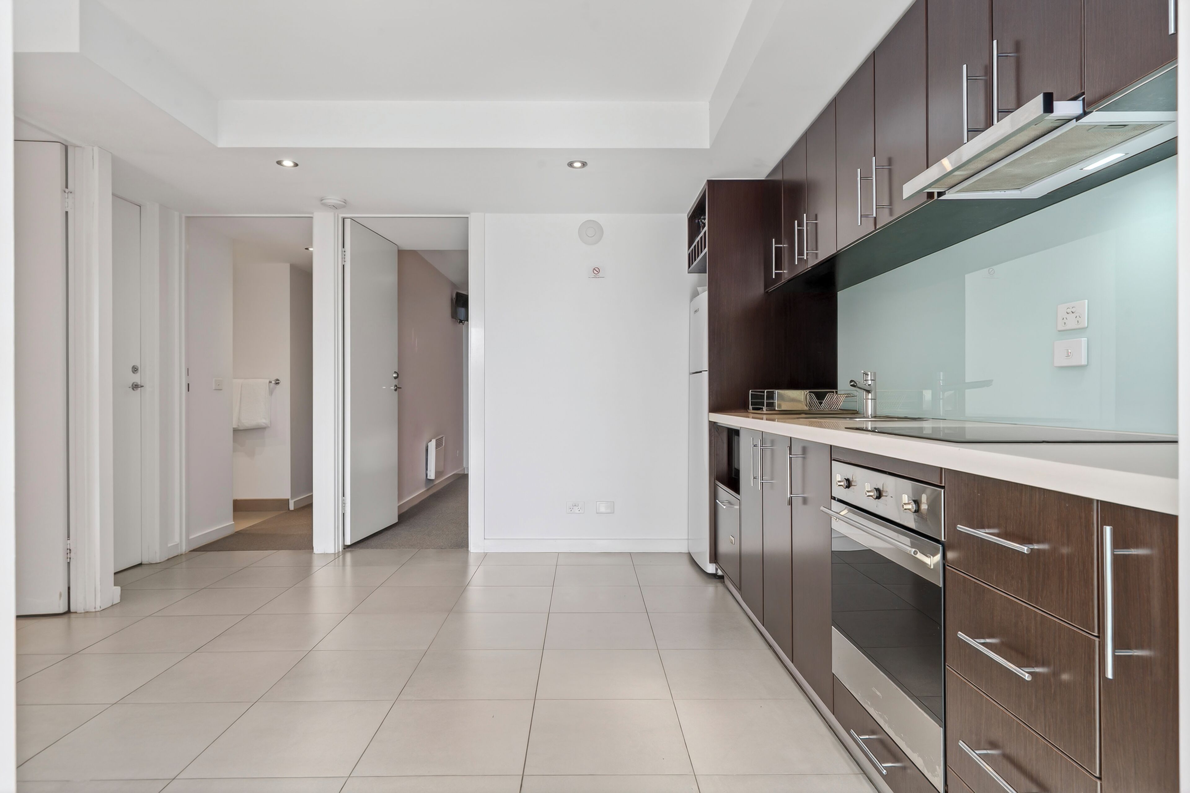 A modern kitchen with stainless steel appliances, wooden cabinets, and a white countertop.