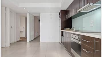 A modern kitchen with stainless steel appliances, wooden cabinets, and a white countertop.
