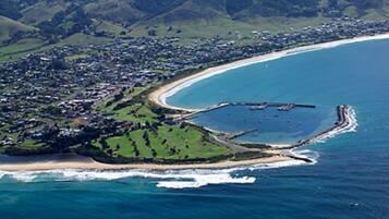 Vista aérea de un pueblo costero con playa, puerto deportivo y zonas residenciales.
