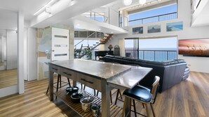 Una cocina moderna con una isla central, un área de comedor con sofá y una escalera que sube a un nivel superior.
