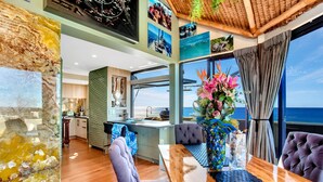 Un comedor moderno con una mesa de madera, sillas acolchadas y un amplio ventanal con vistas al mar.