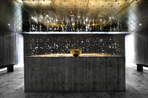 Un interior moderno con una fuente central, suelo de mármol y techo con textura.