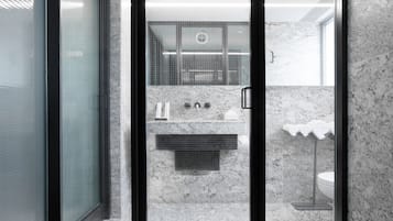A modern bathroom with a glass shower enclosure, a marble sink, and a toilet.