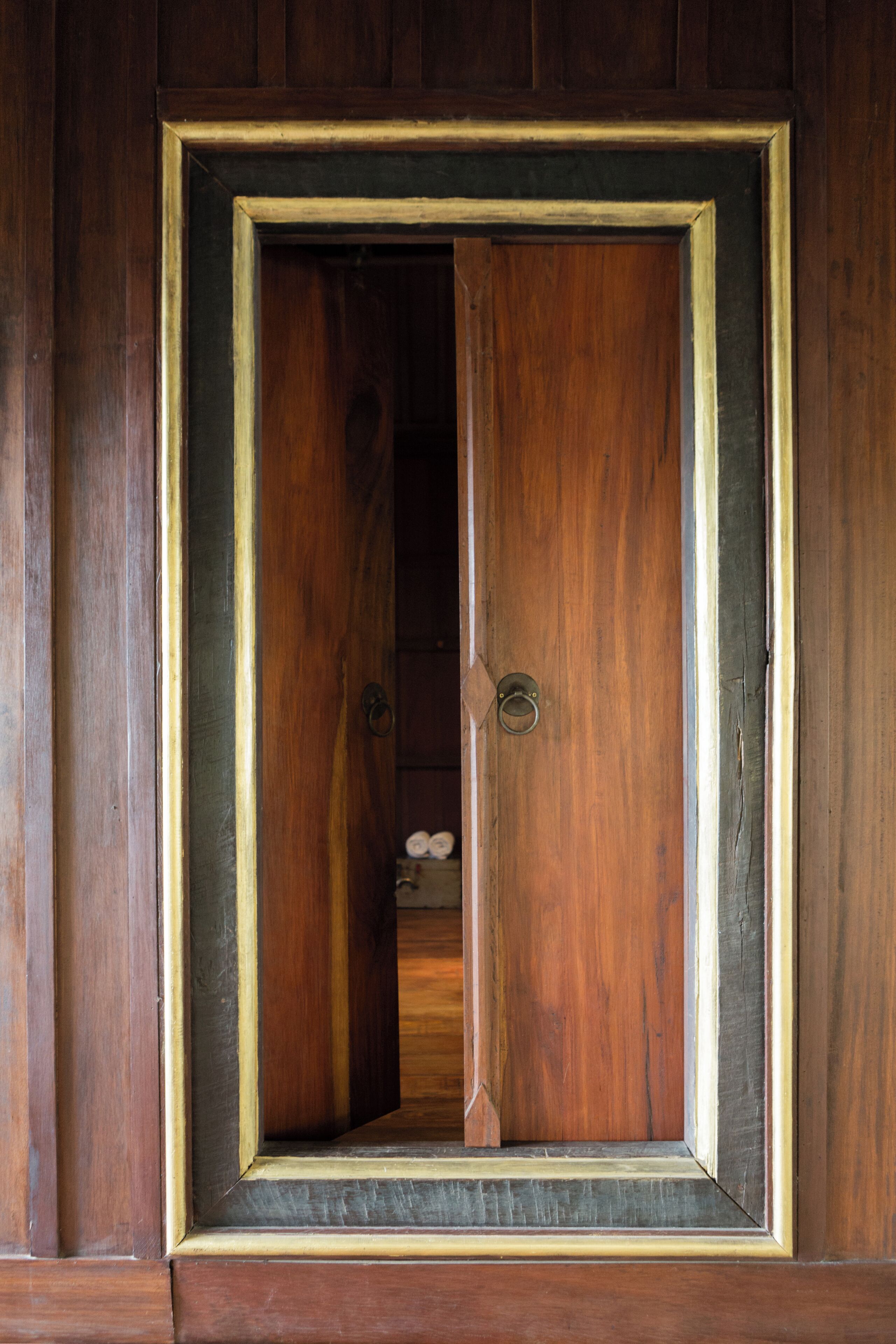 A wooden door with a gold frame, a visible doorknob, and a small keyhole.