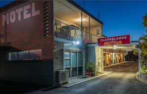 A motel with a balcony, a sign reading "CLAUDELANDS MOTEL," and a paved driveway.