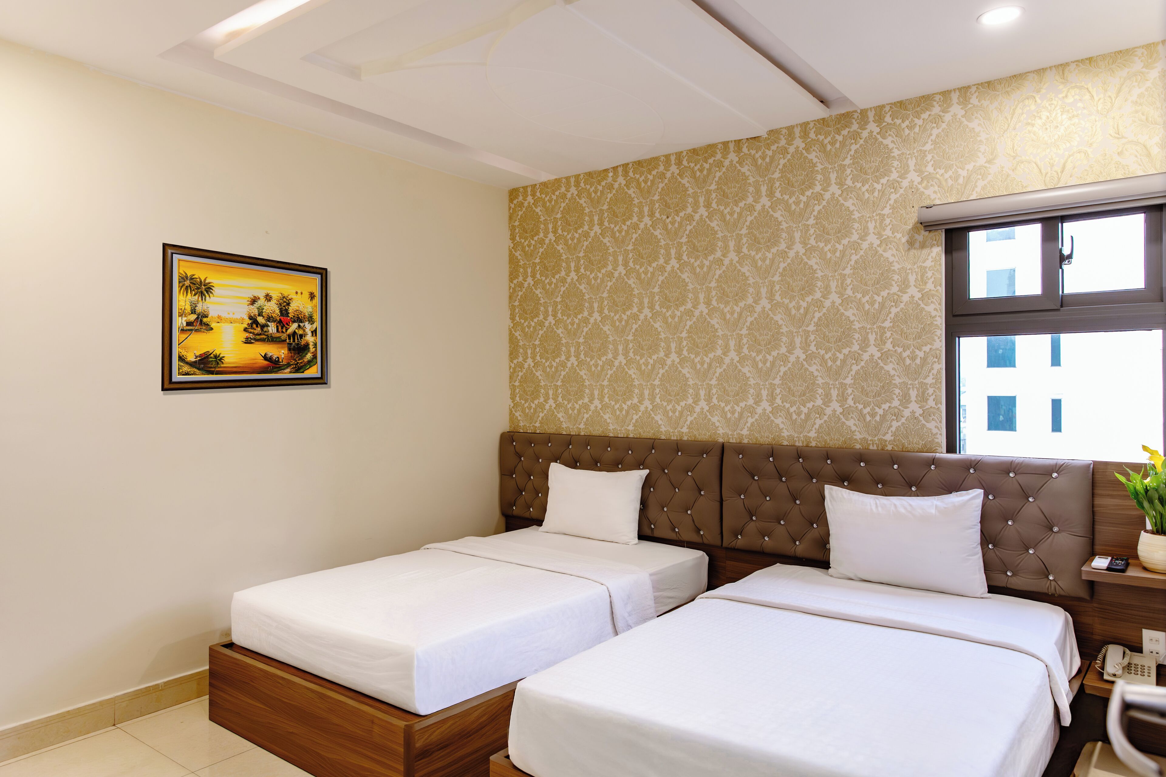 Ein Hotelzimmer mit zwei Betten, einem großen Fenster, einem Bild an der Wand und einem kleinen Tisch mit einer Pflanze.