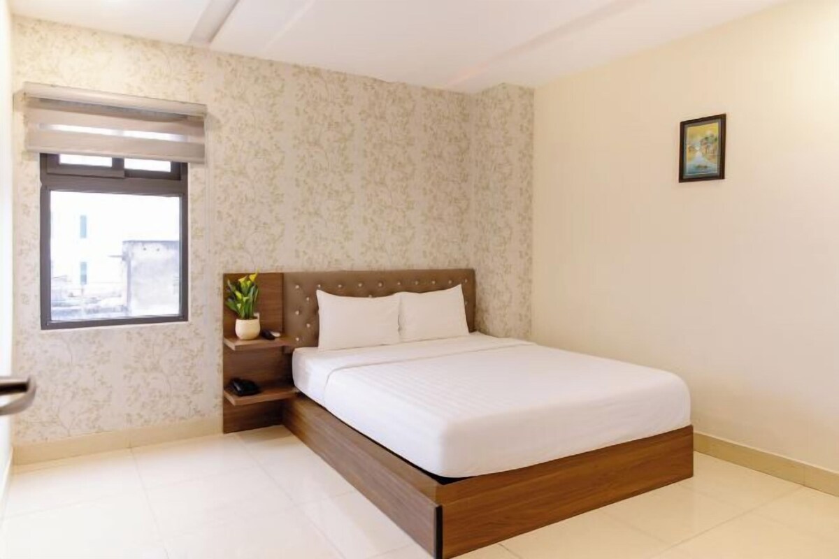 Una camera da letto con un letto, un comodino, una finestra e un quadro appeso al muro.