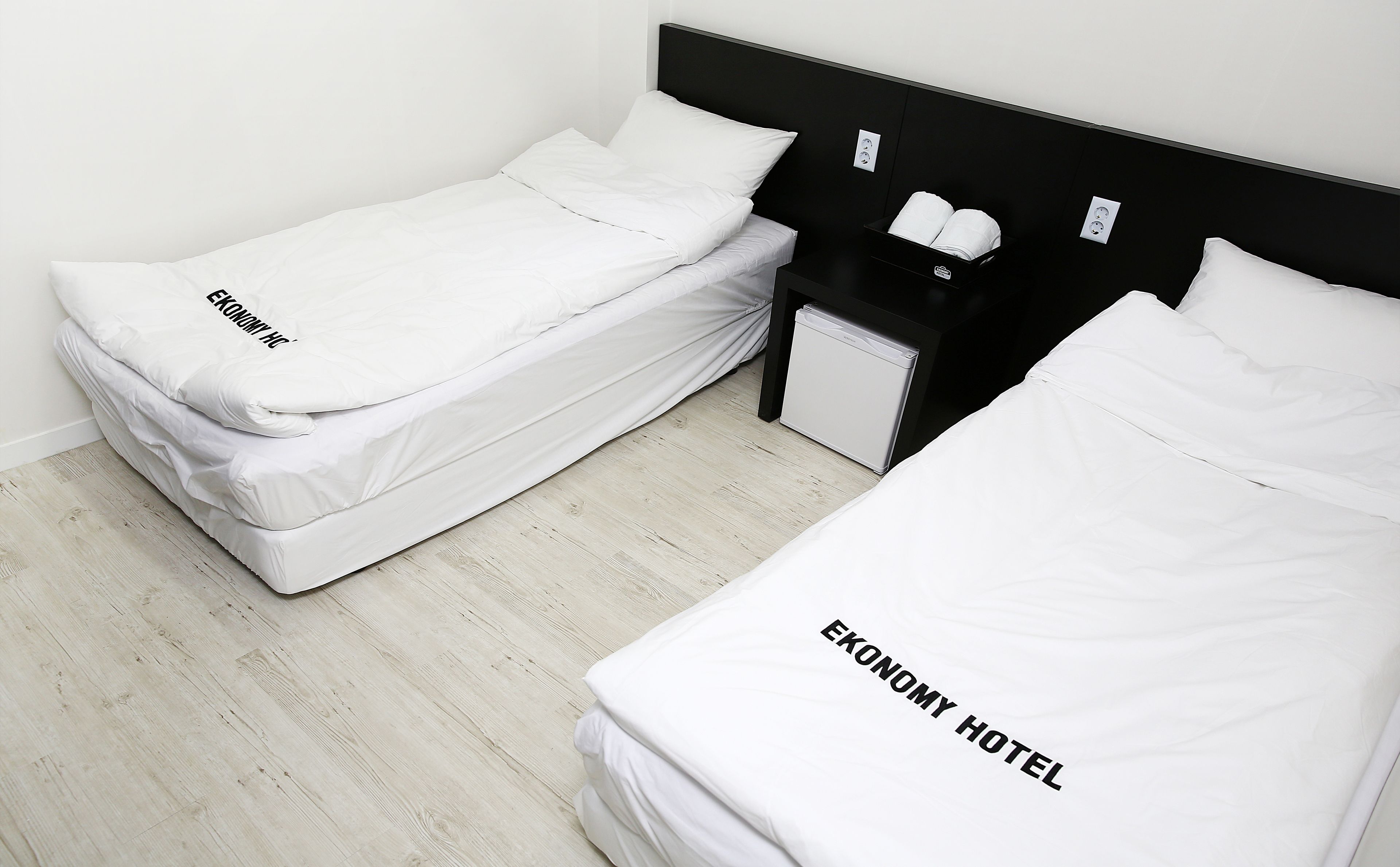 Habitación de hotel con dos camas, cada una con ropa de cama blanca y el texto 