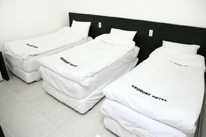 Tres camas individuales con ropa blanca y almohadas, cada una con la etiqueta 'Economy Hotel'.