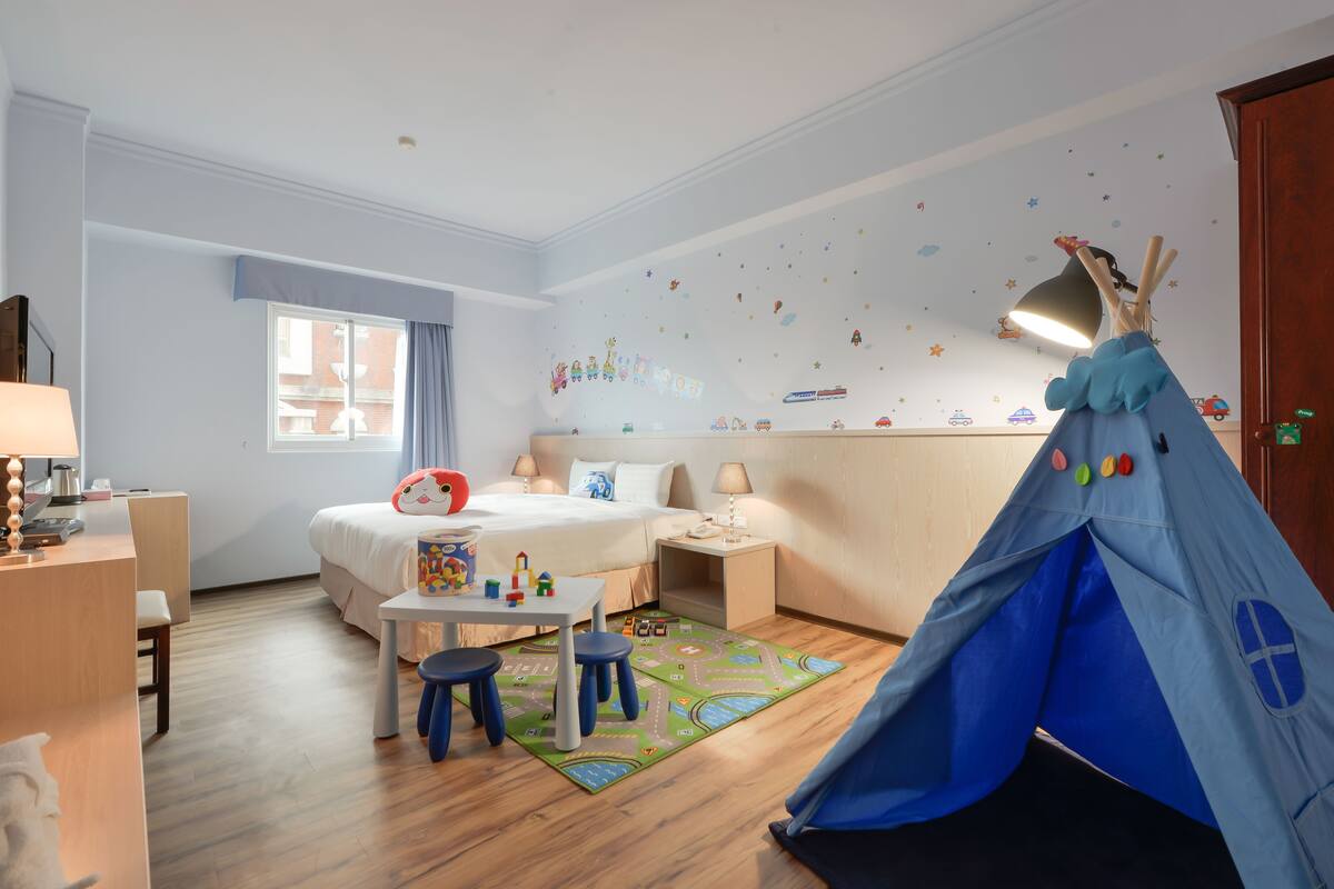 A child-friendly room with a bed, desk, and a play area including a tent.
