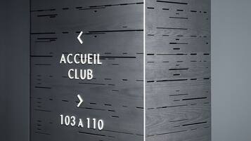 Un panneau de signalisation indiquant « ACCUEIL CLUB » et les numéros de salle « 103 à 110 », le tout sur un mur sombre.